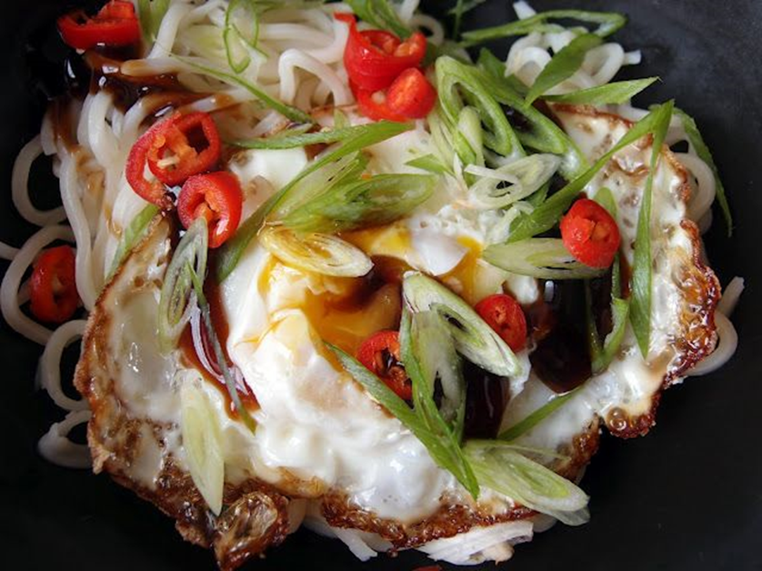Crispy Thai style fried egg garnished with red birdseye chilies and green scallions